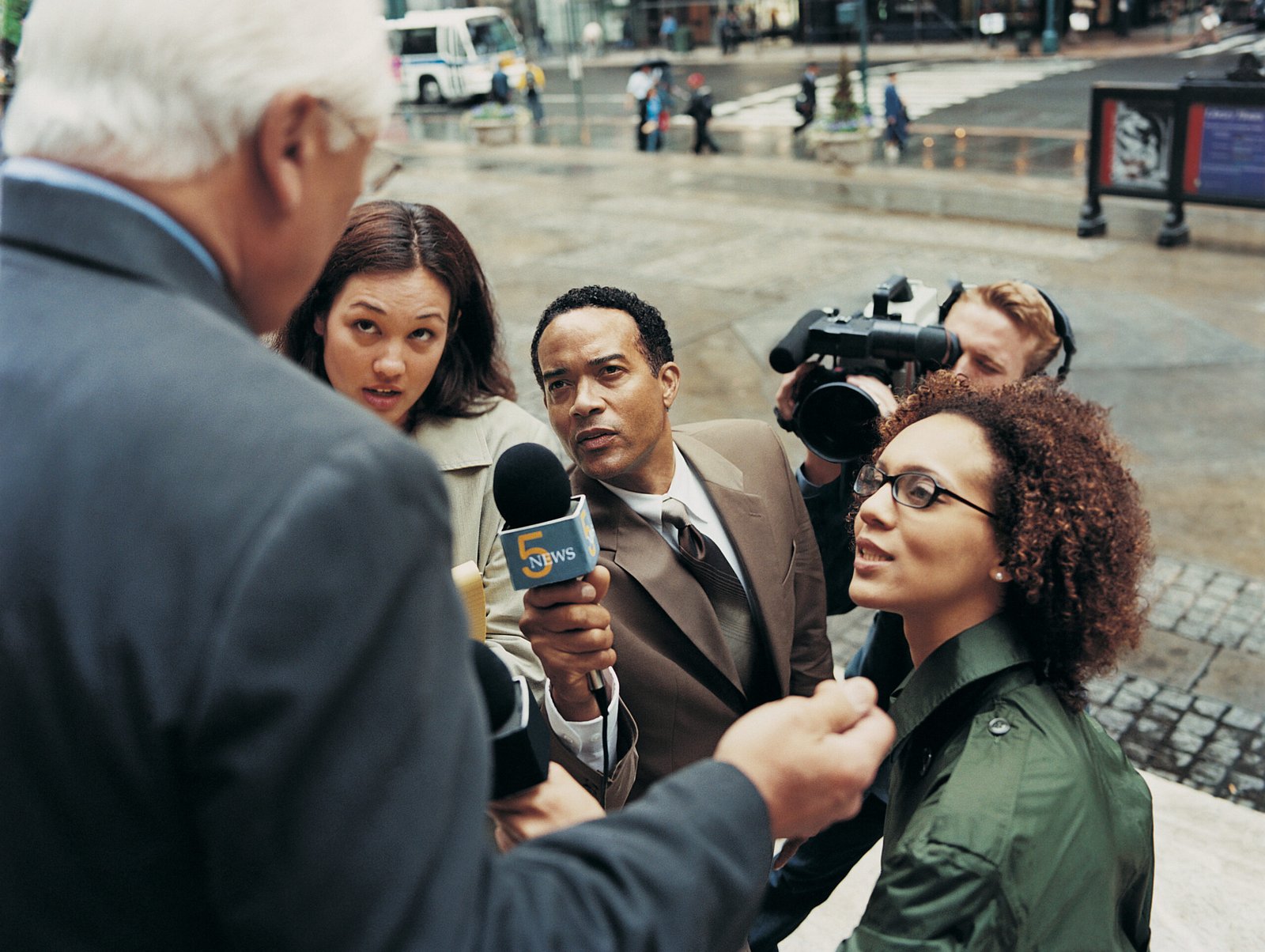 News Reporters and a TV Cameraman Interviewing a Mature Man in the City